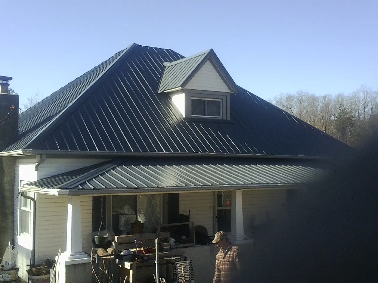 Dark blue standing seam metal roof with a dormer above a front porch in Redding